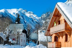 A wooden chalet with a balcony, surrounded by snow-covered mountains and a clear blue sky. - Proche des pistes | Piscine & Sauna sur place (Saint-Colomban-des-Villards)