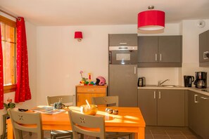 Cocina compacta con comedor, que incluye una mesa, sillas y una lámpara colgante roja.
