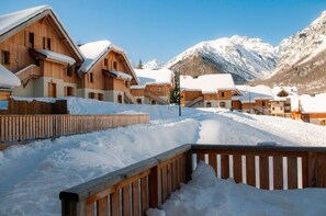 A snow-covered wooden chalet with a wooden fence in the foreground. - Proche des pistes | Piscine int/ext | Duplex (Saint-Colomban-des-Villards)