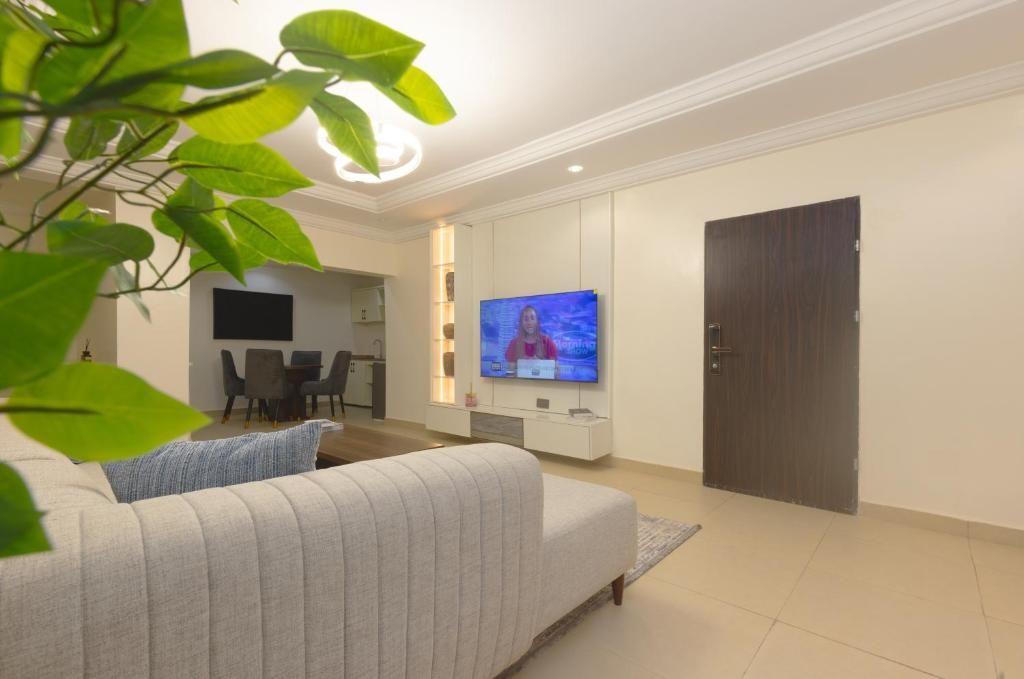Una sala de estar moderna con un televisor de pantalla plana, un sofá, un comedor y una puerta cerrada.