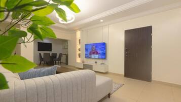 Una sala de estar moderna con un televisor de pantalla plana, un sofá, un comedor y una puerta cerrada.