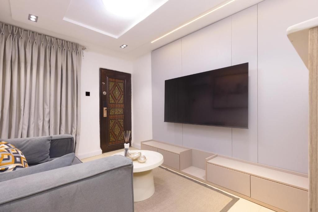 Una sala de estar moderna con un sofá, una mesa de centro, un televisor montado en la pared y una puerta decorativa.