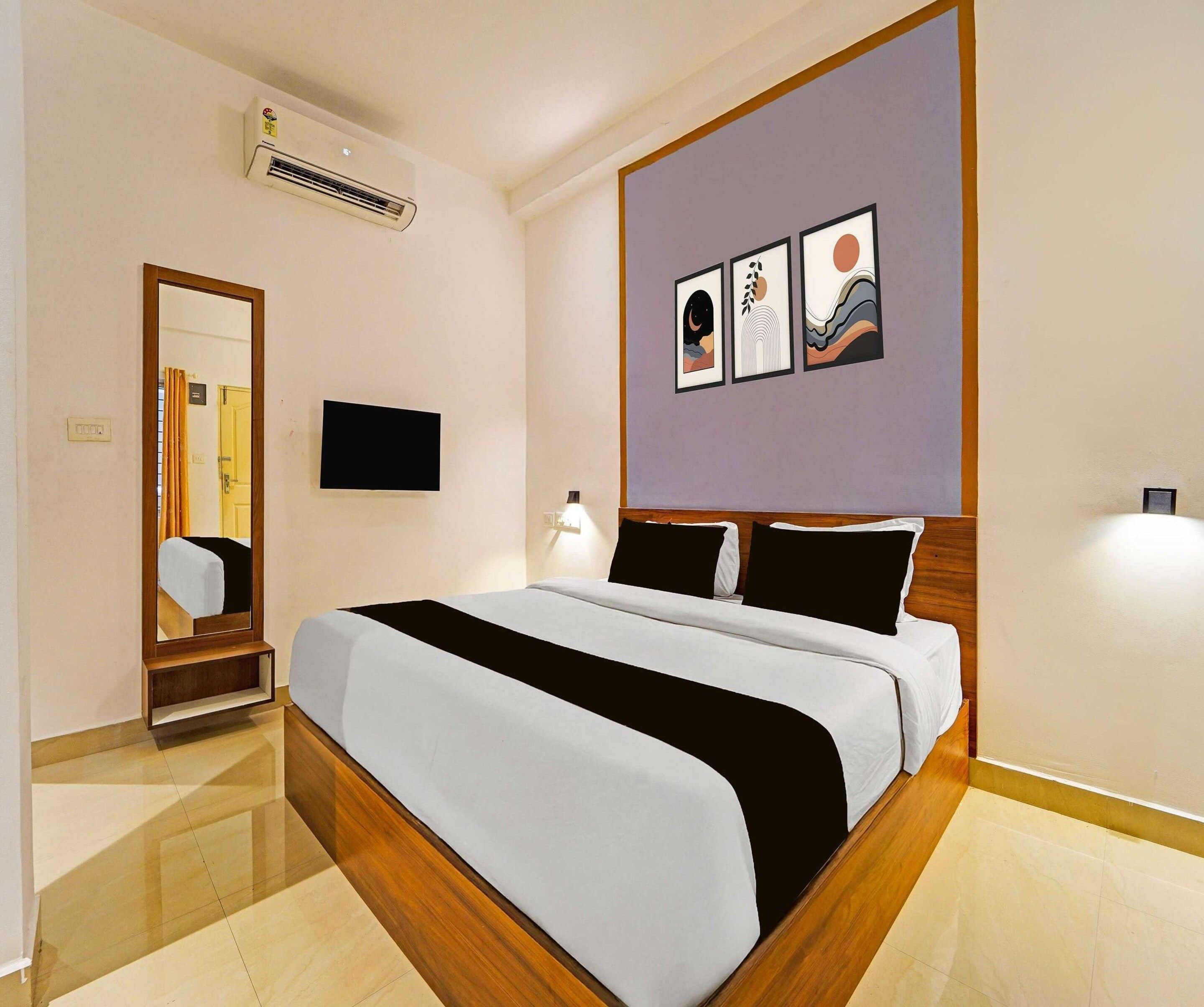 Una camera d'albergo con un letto, una TV a schermo piatto, un condizionatore d'aria a muro e uno specchio.
