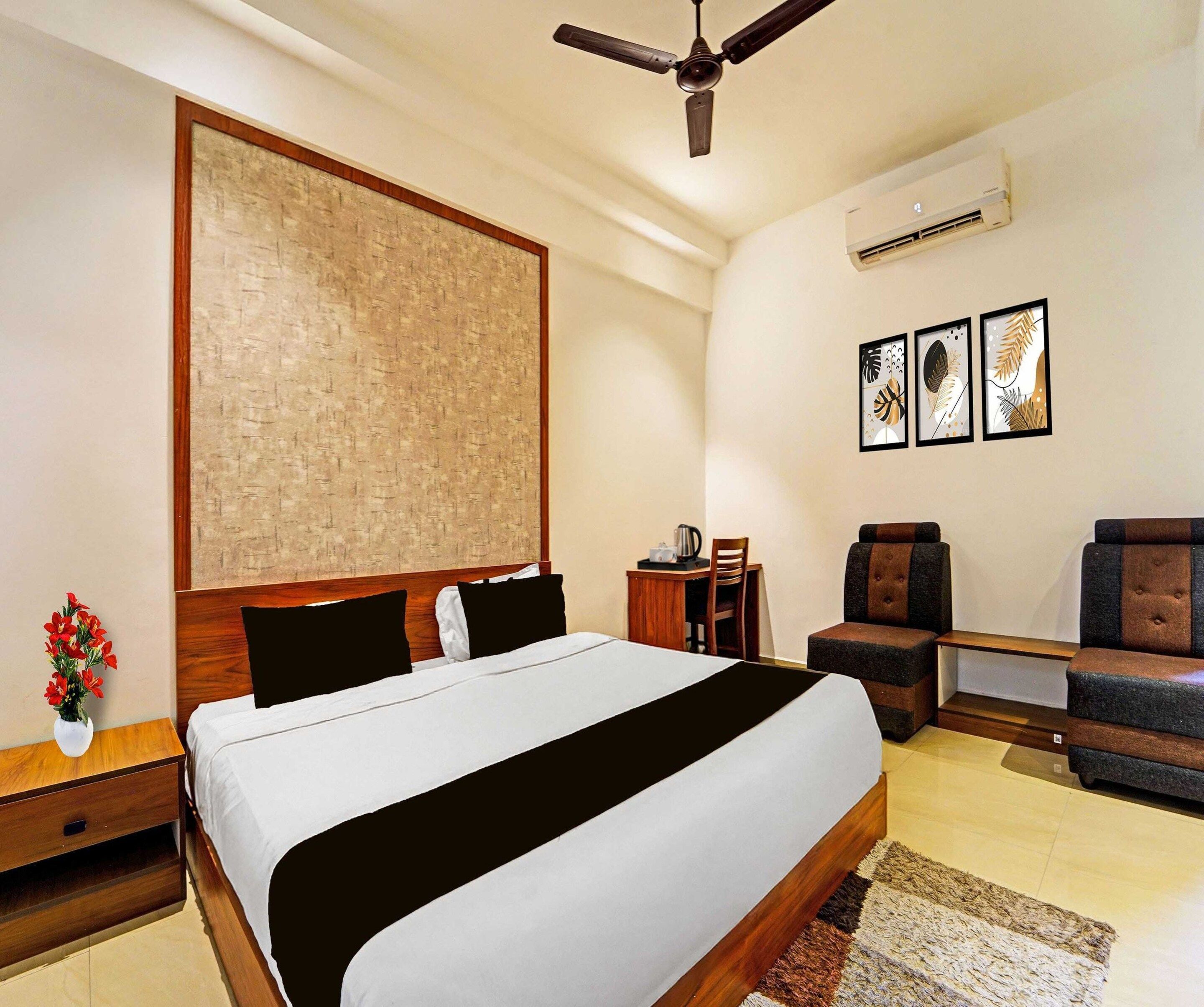 A hotel room with a bed, a desk, a chair, a ceiling fan, and wall art.