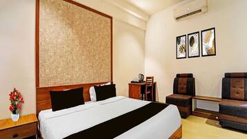 A hotel room with a bed, a desk, a chair, a ceiling fan, and wall art.