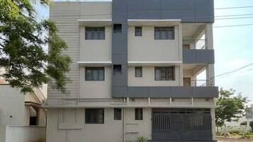 A modern multi-story building with a flat facade, multiple windows, and a gated entrance.