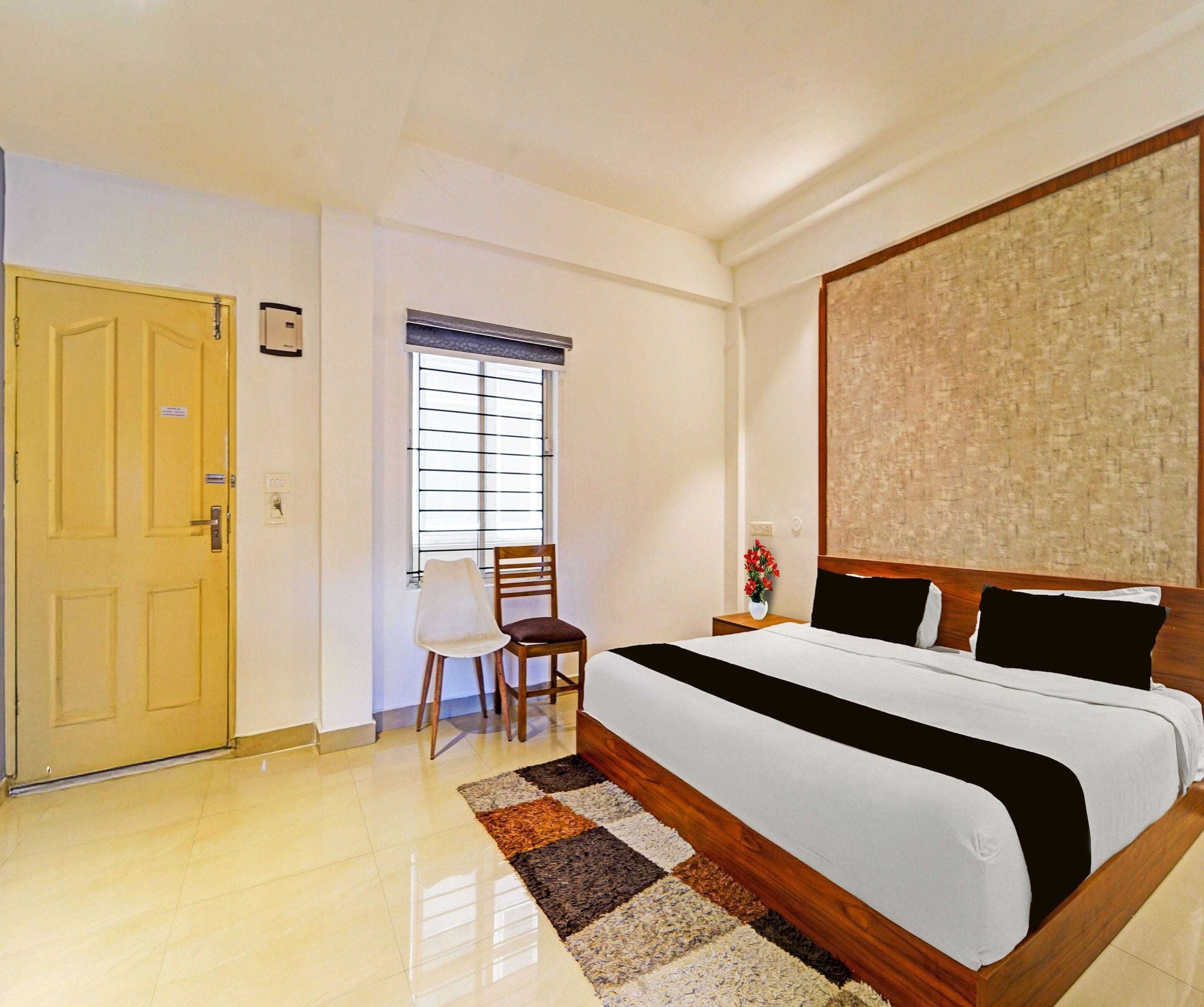 Een hotelkamer met een bed, een stoel, een raam met zonwering en een deur.