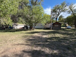 A fenced yard with a small cabin, a utility shed, and a large white tank.