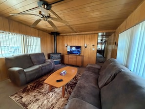 A living room with a sofa, a coffee table, a television, and a ceiling fan.