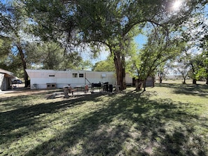 A mobile home with a patio area, a barbecue grill, and a small table and chairs.