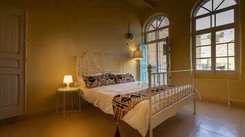 Ein Schlafzimmer mit Bett, Nachttischlampe, Fenster und Tür.