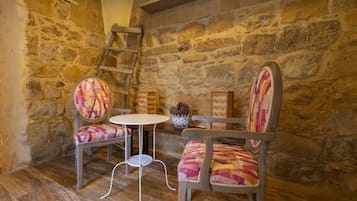 Un intérieur rustique avec un mur en pierres apparentes, une table en bois et deux chaises à motifs.