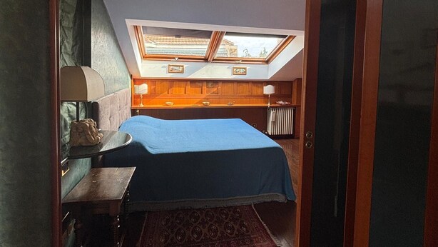 Ein Schlafzimmer mit Oberlicht, einem Bett, einem Nachttisch und einer Heizung.