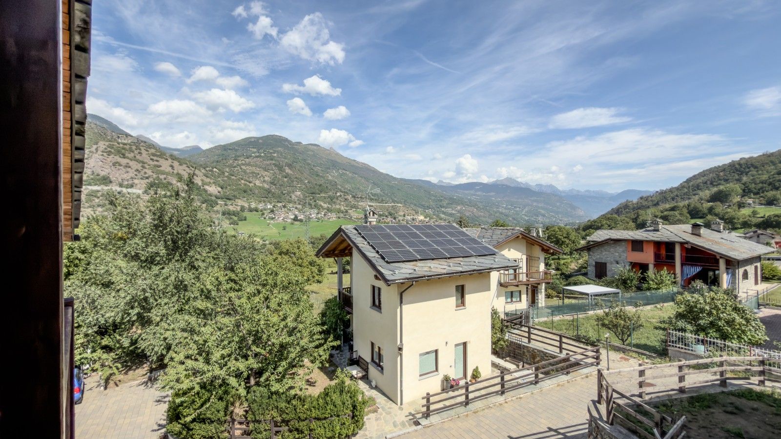 Un paysage de montagne avec un bâtiment doté d’un balcon et de panneaux solaires.