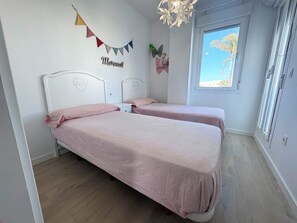 A bedroom with two beds, a window with a view, and a wall decoration. - Luz de Conil: Style and comfort just steps from the beach. (Conil de la Frontera)