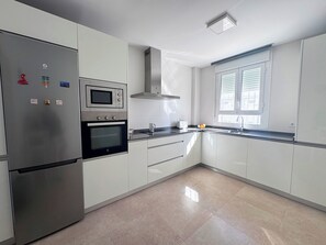 A modern kitchen with stainless steel appliances, a window with blinds, and a tiled floor. - Luz de Conil: Style and comfort just steps from the beach. (Conil de la Frontera)