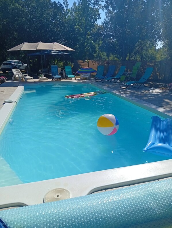 A swimming pool with lounge chairs and a beach ball.