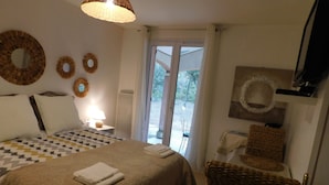 Ein Hotelzimmer mit einem großen Bett, einer Sitzecke mit einem Sessel, einem Tisch und einem Balkon mit Blick.
