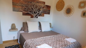 Ein Schlafzimmer mit einem Bett, Kissen, einem Nachttisch, einem Wandbild und einer dekorativen Wandverziierung.