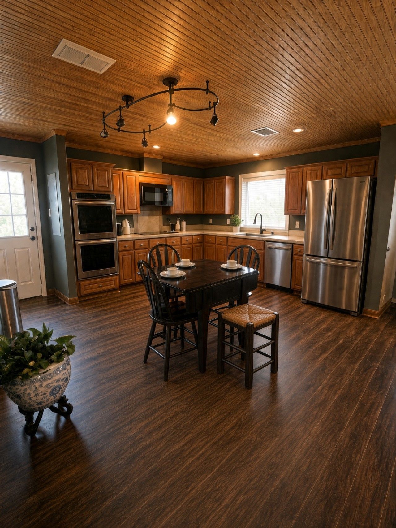Une cuisine moderne avec des meubles en bois, des appareils électroménagers en acier inoxydable et un coin repas comprenant une table et des chaises.