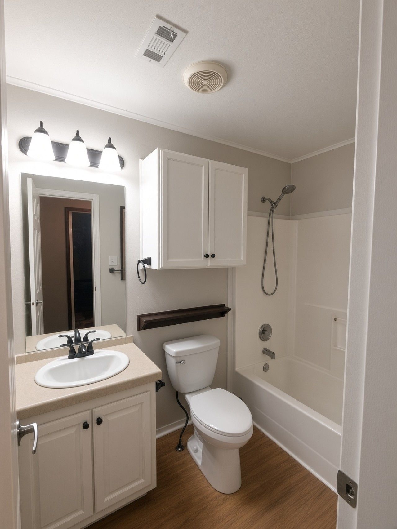 A bathroom with a white sink, mirror, cabinet, toilet, and shower.