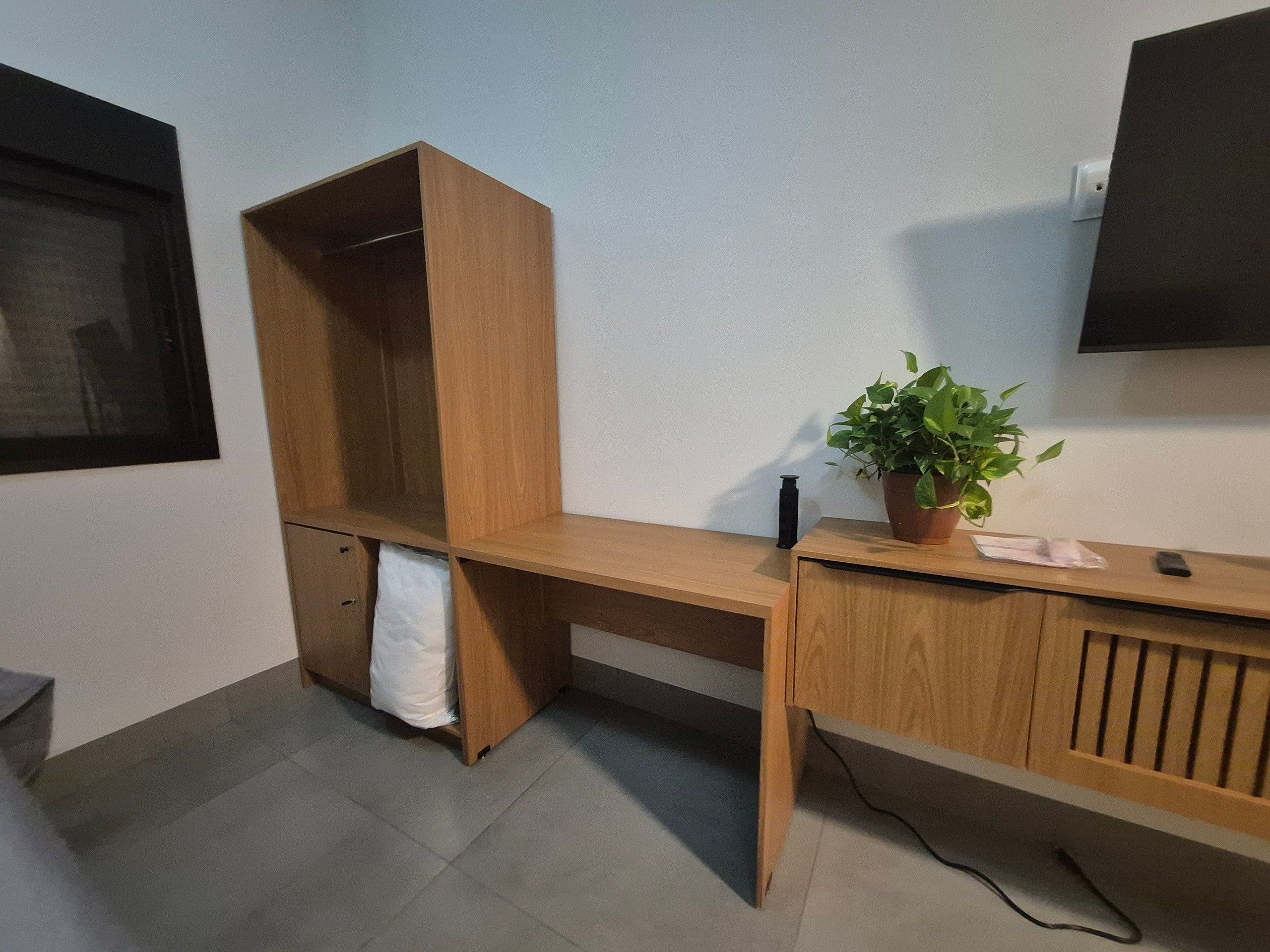 A wooden desk with a potted plant, a towel, and a black object on it.