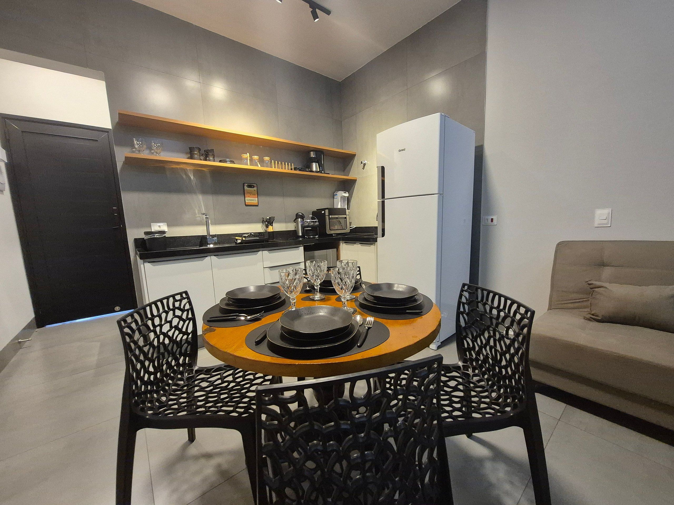 A modern kitchen with a dining area, including a round table with chairs, a refrigerator, and a sofa.