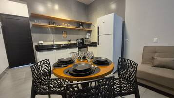 A modern kitchen with a dining area, including a round table with chairs, a refrigerator, and a sofa.