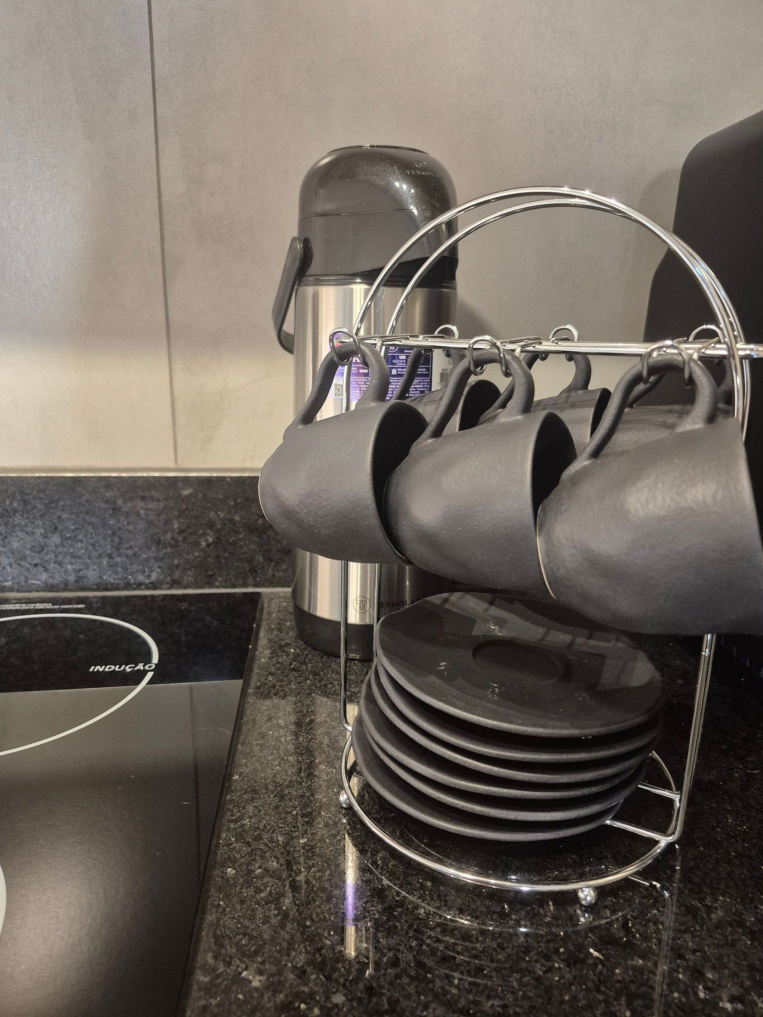 A kitchen counter with a kettle, a coffee maker, and a stack of plates.