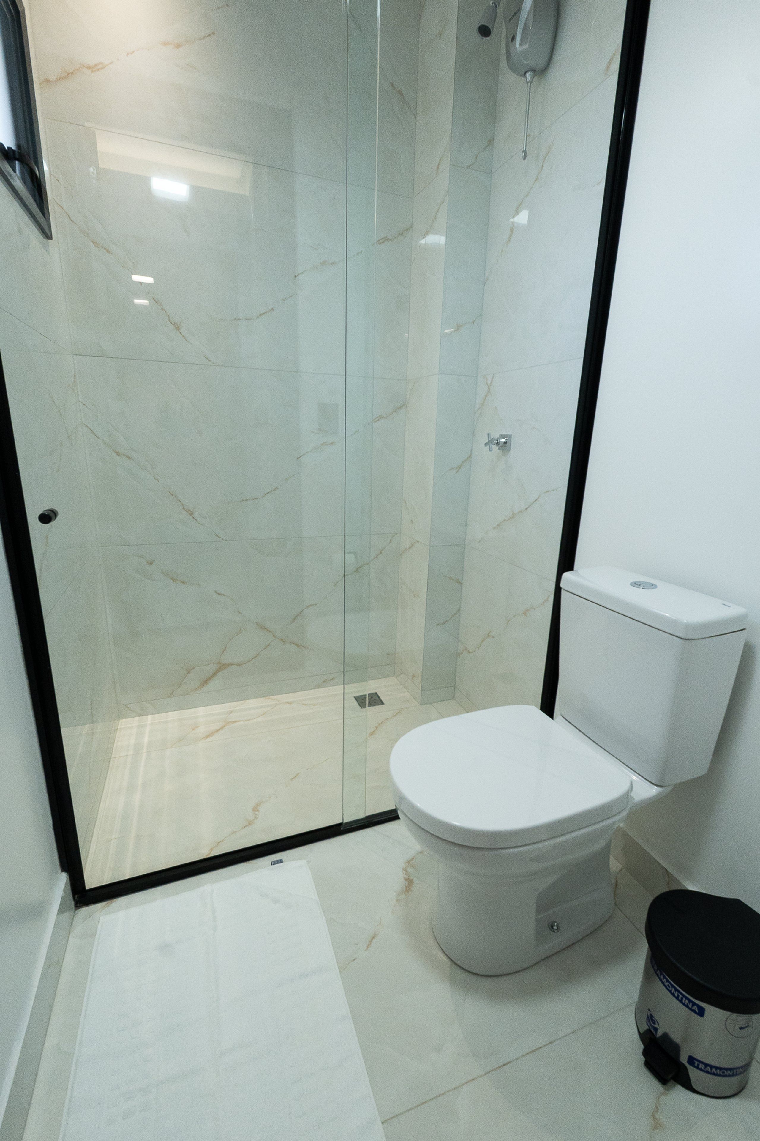 Un baño con ducha de vidrio, inodoro blanco y lavamanos blanco.