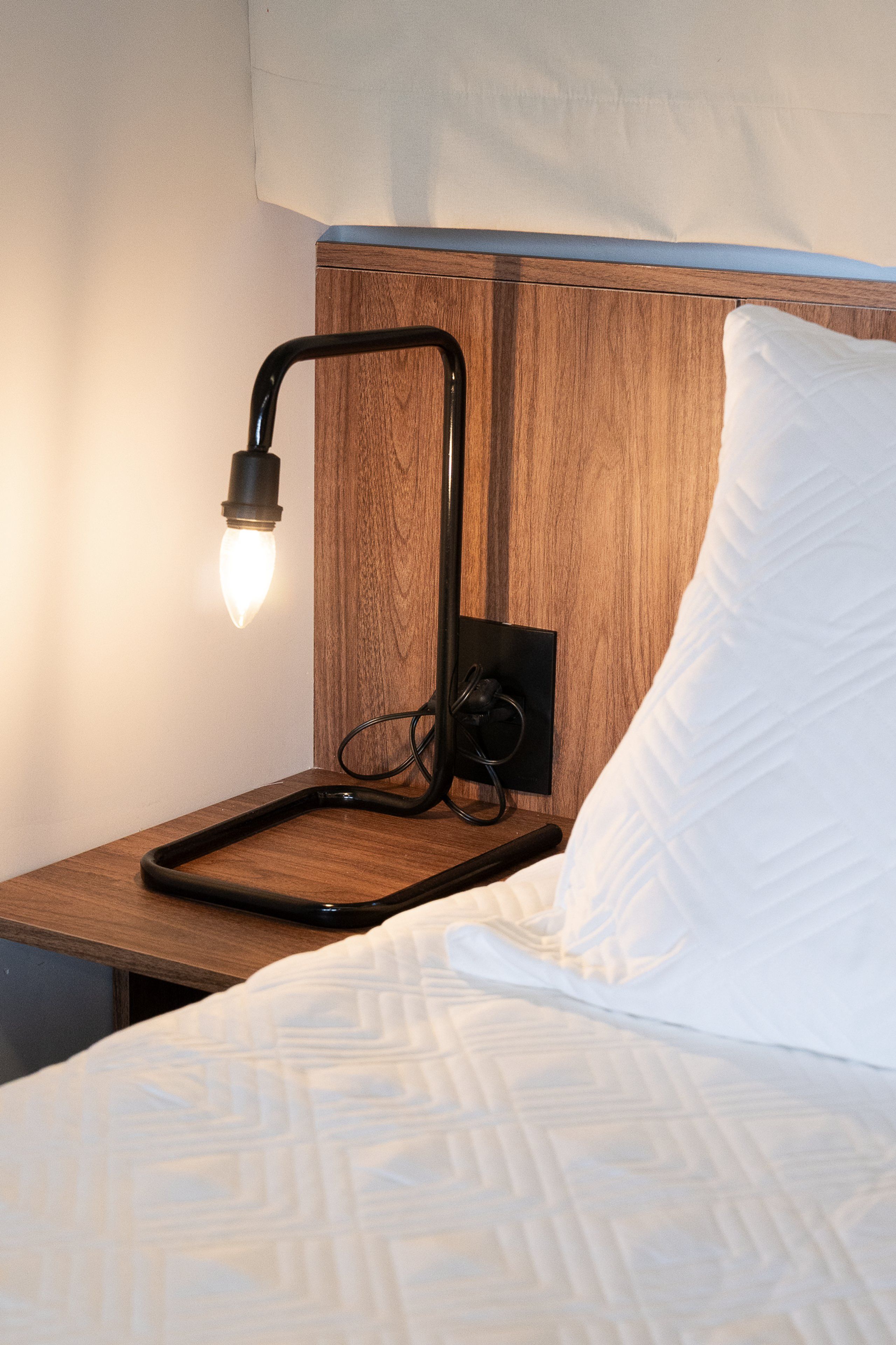 A bed with a white pillow and a wooden headboard.