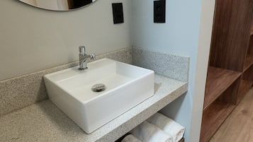 Ein Badezimmer mit einem weißen Waschbecken, einem Spiegel und einem Handtuchhalter.