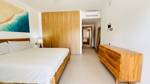 Ein Hotelzimmer mit einem Bett, einem Holzkoffer, einem Bild an der Wand und einer Tür zu einem anderen Raum.