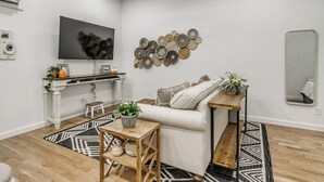 Ein modernes Wohnzimmer mit einer Couch, einem Couchtisch, einem an der Wand montierten Fernseher und einem Deckenventilator.