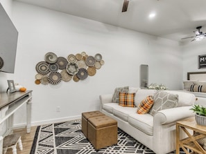 A living room with a white sofa, patterned rug, and wall decor.