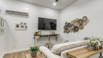 Een moderne woonkamer met een bank, een salontafel, een televisie en decoratieve muurkunst.
