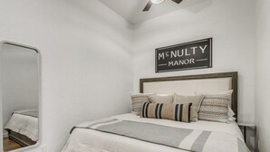 Ein Schlafzimmer mit einem Bett, einem Spiegel, einem Deckenventilator und einem Schild über dem Bett.
