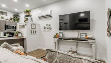 Una sala moderna con un televisor de pantalla plana, una chimenea y una cocina al fondo.