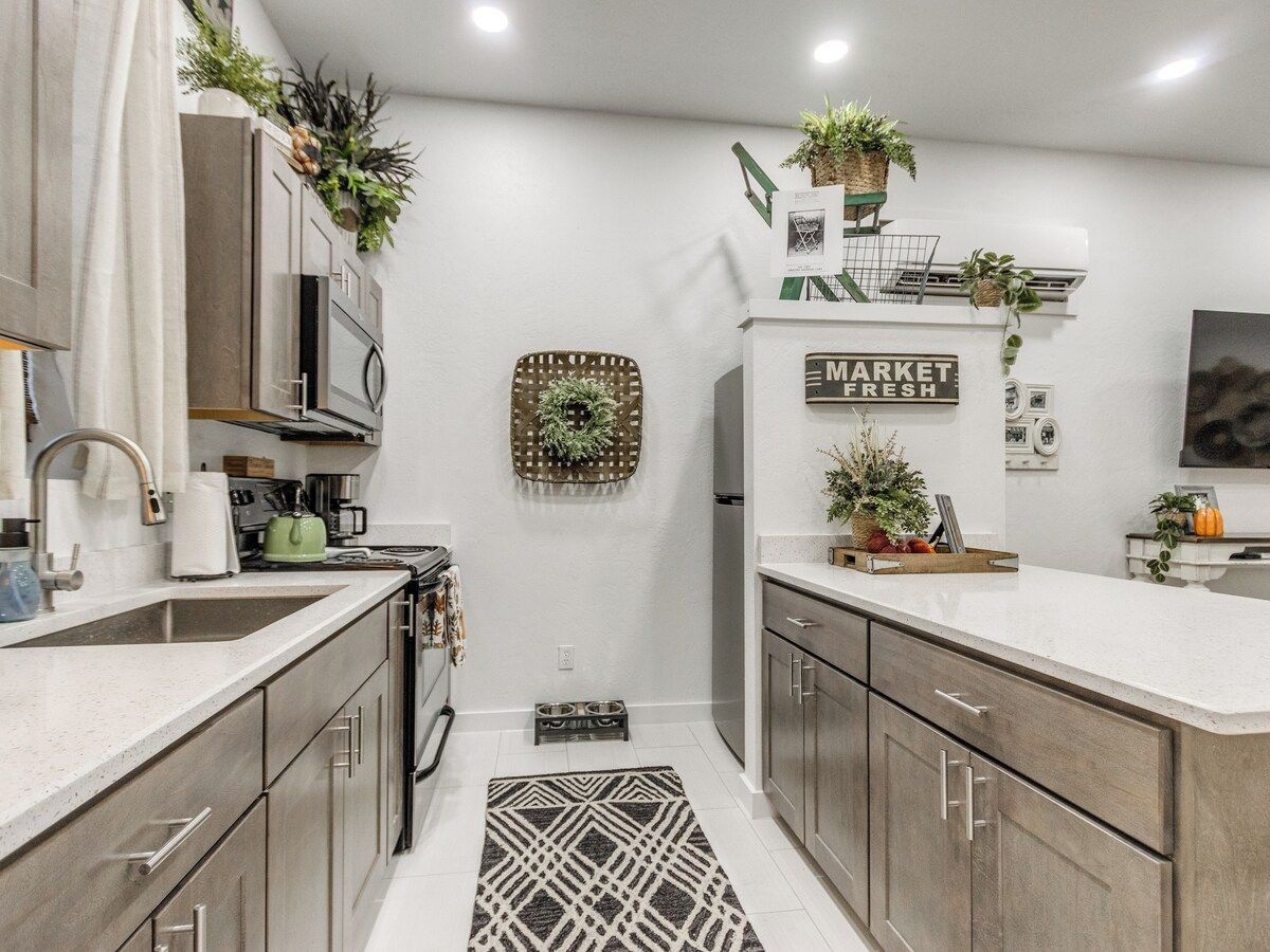 A modern kitchen with a central island, stainless steel appliances, and decorative plants.