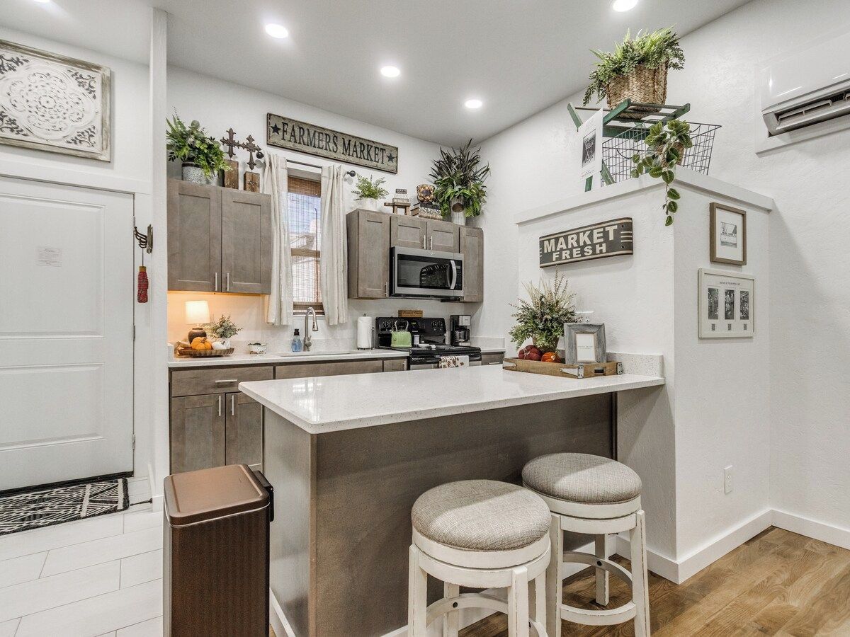A kitchen with a central island, bar stools, a microwave, and a sign that reads 'FARMERS MARKET'.