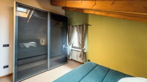 A bedroom with a sliding glass door, a bed with a blue mattress, a radiator, and a window with curtains. - Abri Douillet (Saint-Marcel)