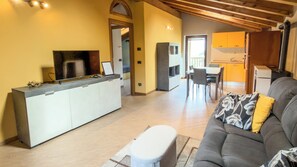 A modern living room with a sofa, a small table, and a kitchen area in the background. - Abri Douillet (Saint-Marcel)