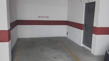 A parking garage with a red and white wall, a door, and a visible emergency exit sign.