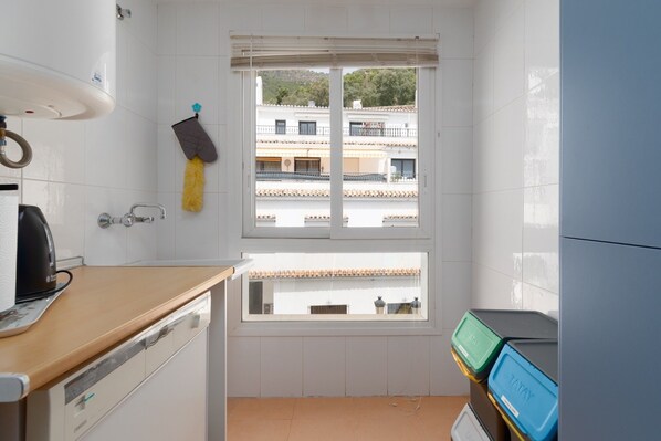 A small kitchen with a window, a sink, a stove, and a countertop.