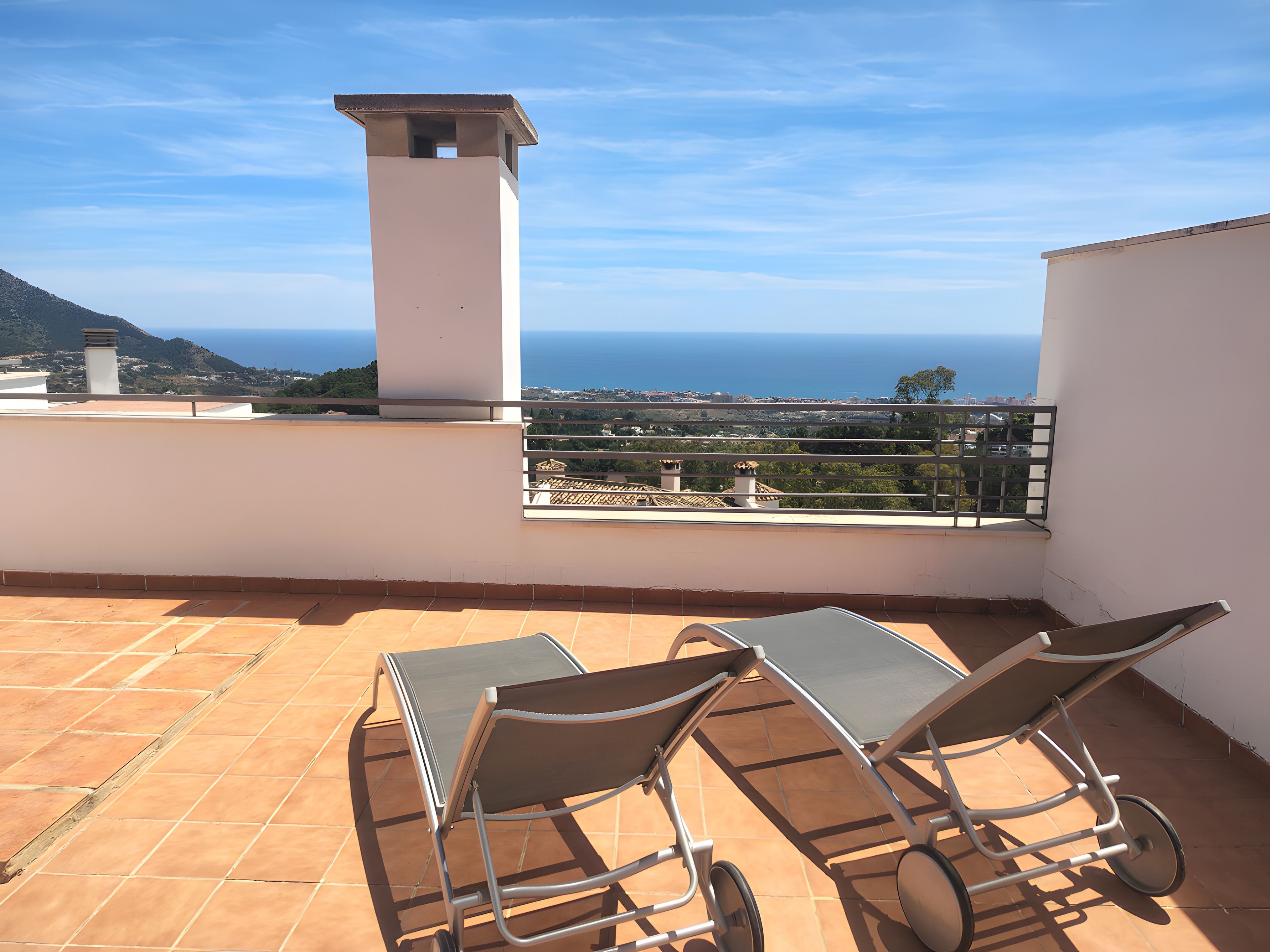 A terrace with two sun loungers and a view of the sea.