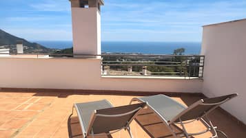 A terrace with two sun loungers and a view of the sea.