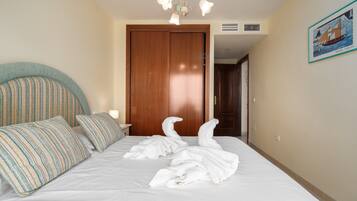 Une chambre d’hôtel avec un lit, une porte en bois, un climatiseur fixé au mur et un tableau encadré accroché au mur.