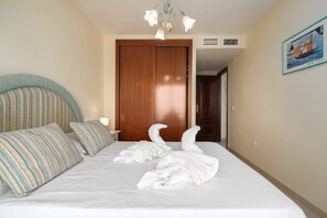 A hotel room with a bed, a wooden door, a wall-mounted air conditioner, and a framed picture on the wall.