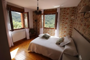A bedroom with a bed, two windows, a radiator, and a chair. - Country House 'El Mirador De Jozarcu' with Mountain View, Balcony and Wi-Fi (Navedo)