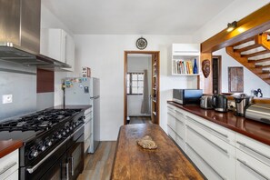 A kitchen with a stove, refrigerator, and wooden countertop. - Peaceful stay in the heart of a mountain village, with views of the pyrenees. (Égat)